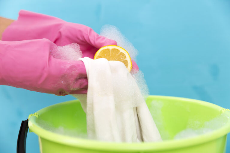 close up of cleaner woman hand removing stain from white cloth with lemon